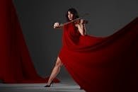 Love, as an emotion. 2 Violinist in a flowing red dress playing indoors, exuding elegance and poise.