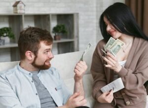 Is Money Important in Love? 2 A cheerful couple managing their finances at home, holding cash and a receipt.