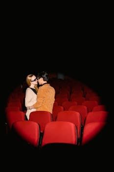 Love and Dating Trends: The Rise of Thoughtful Gestures Over Grand Romantic Displays 2 A couple kissing in a movie theater surrounded by red seats under a spotlight.