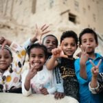The Seven Pillars of Happiness: Building a Life of Joy and Fulfillment.(Group of smiling children gesturing peace signs outdoors in Tarim, Yemen.)