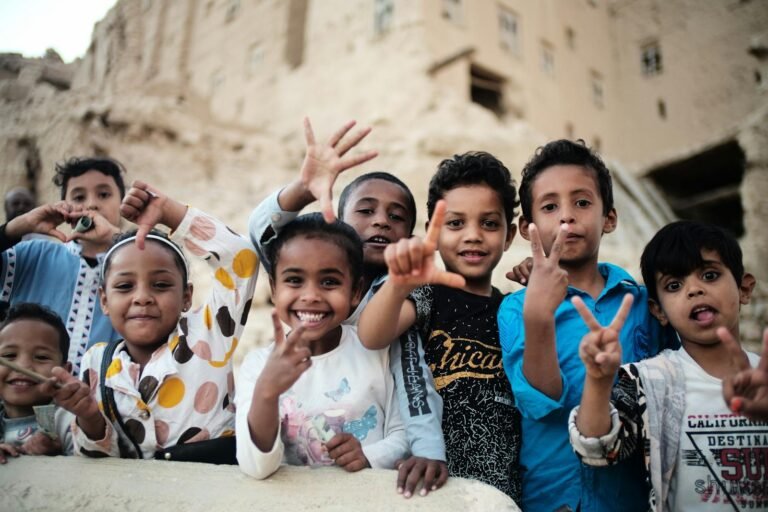 The Seven Pillars of Happiness: Building a Life of Joy and Fulfillment.(Group of smiling children gesturing peace signs outdoors in Tarim, Yemen.)