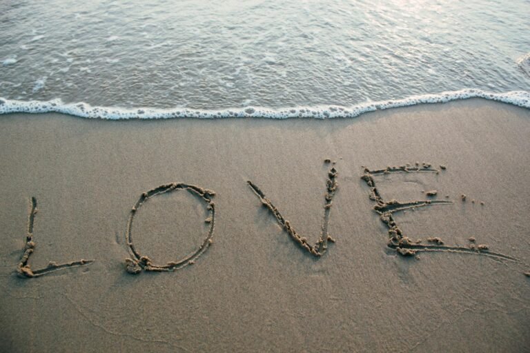 Love and Health in 2025: How Emotional Wellness Shapes Physical Vitality.(Love written in sand with ocean waves at the beach, evoking romance and tranquility.)