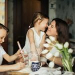 The Unwavering Anchor: A Symphony of Mothers' Love and Care.(A joyful moment of a mother baking with her children in a cozy home environment.)