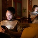 Digital Relationship Resilience: Building Stronger Bonds in the Connected World (Part 2) love,health, A couple enjoying a cozy evening in a warm home, both using smartphones.