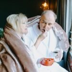 The Tapestry of Love and Sex: A Vital Thread in the Human Experience in 2025.(Warm moment shared by a senior couple in bathrobes, enjoying chocolates and a beverage by the window.)