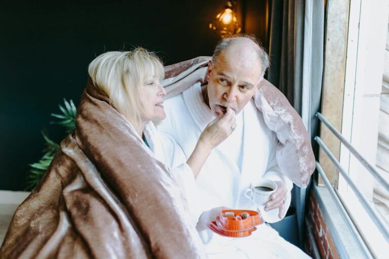The Tapestry of Love and Sex: A Vital Thread in the Human Experience in 2025.(Warm moment shared by a senior couple in bathrobes, enjoying chocolates and a beverage by the window.)