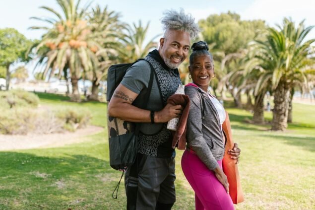 2025 Guide: Love – The Ultimate Secret Weapon for Your Wellness and Health.(Happy senior couple practicing yoga outdoors in a park setting, promoting wellness and togetherness.)