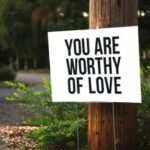 Love and Health Future: 10 Transformative Affirmations to Boost Your Love, Health, and Happiness.(A positive message sign "You are worthy of love" in a park setting.)