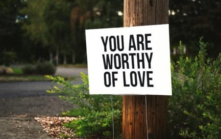Love and Health Future: 10 Transformative Affirmations to Boost Your Love, Health, and Happiness.(A positive message sign "You are worthy of love" in a park setting.)